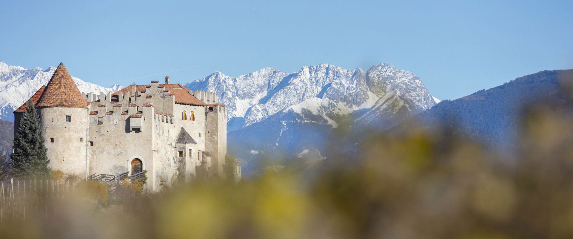 Kastelbell Castle Castle is enthroned in front of the imposing peaks of the snow-covered mountains.